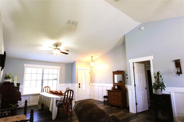 dining room featuring a textured ceiling, vaulted ceiling, ceiling fan, and dark wood-type flooring