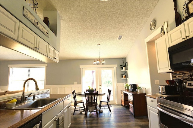 kitchen featuring sink, hanging light fixtures, stainless steel range oven, a textured ceiling, and white cabinets