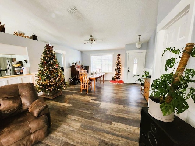 living room with a textured ceiling, ceiling fan, and dark hardwood / wood-style floors