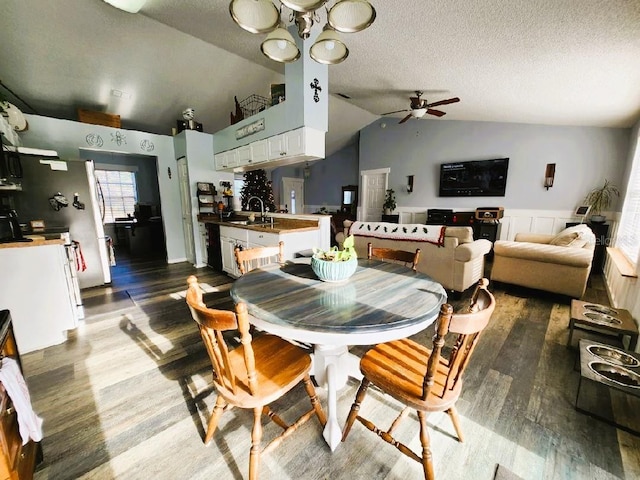 dining area featuring a textured ceiling, ceiling fan, sink, dark hardwood / wood-style floors, and lofted ceiling