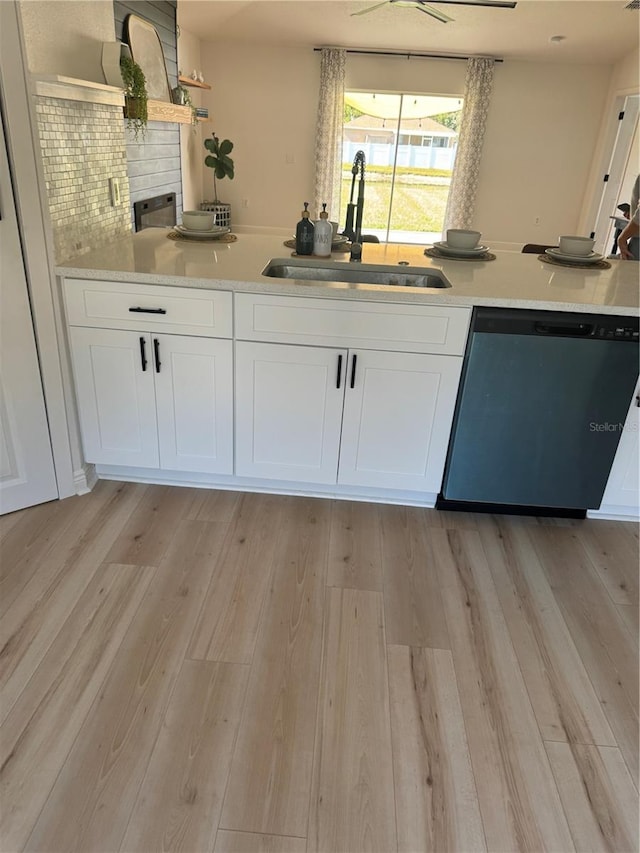 kitchen with white cabinetry, sink, stainless steel dishwasher, and light hardwood / wood-style flooring