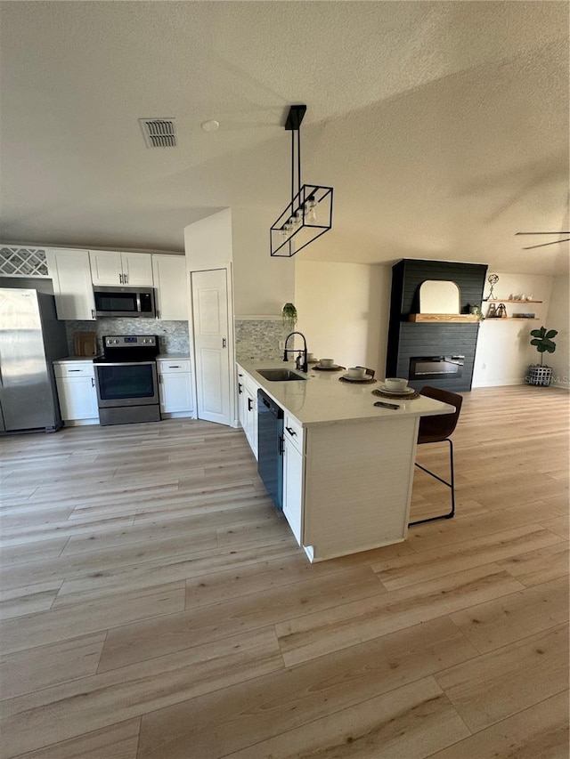 kitchen with sink, stainless steel appliances, decorative light fixtures, decorative backsplash, and white cabinets