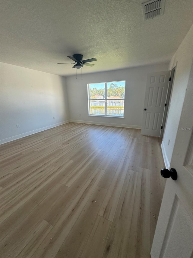 empty room with a textured ceiling, light hardwood / wood-style floors, and ceiling fan