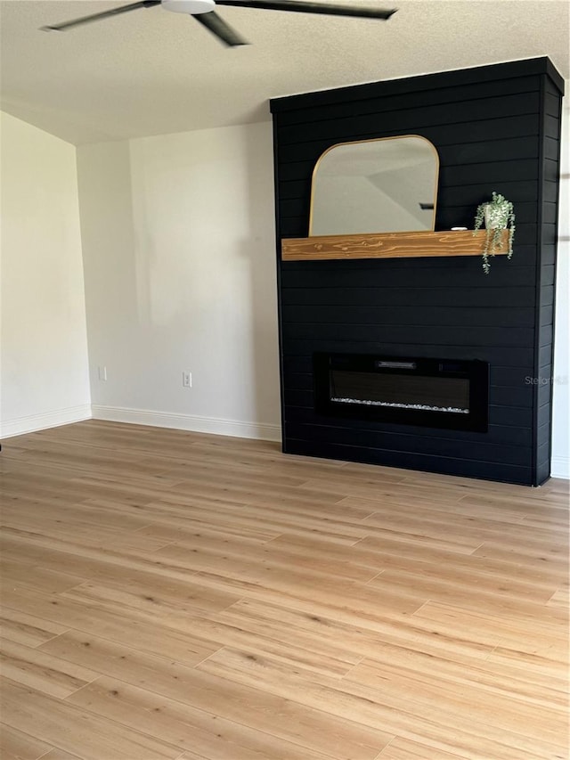 interior details featuring hardwood / wood-style flooring, ceiling fan, and a large fireplace