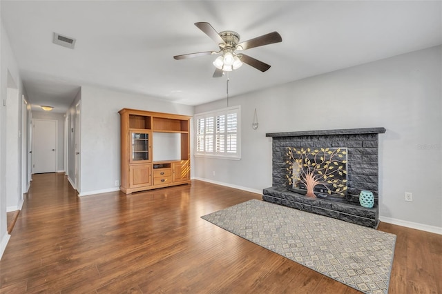 unfurnished living room with a fireplace, dark hardwood / wood-style floors, and ceiling fan