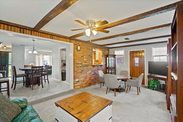 living room with beam ceiling, plenty of natural light, light colored carpet, and brick wall