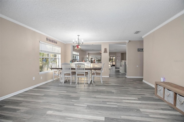 dining space featuring a textured ceiling, hardwood / wood-style flooring, crown molding, and a notable chandelier