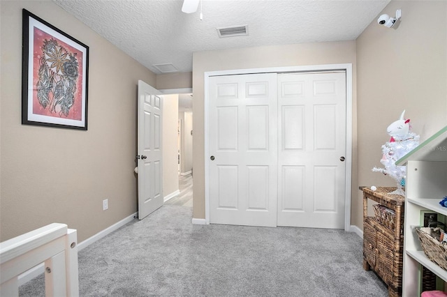 carpeted bedroom with ceiling fan, a closet, and a textured ceiling