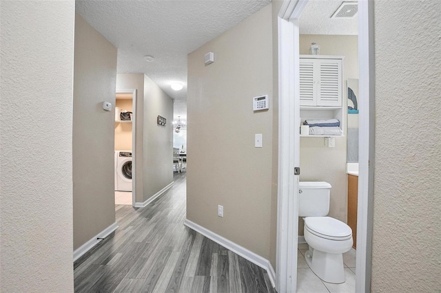 hall featuring hardwood / wood-style floors, a textured ceiling, and washer / clothes dryer