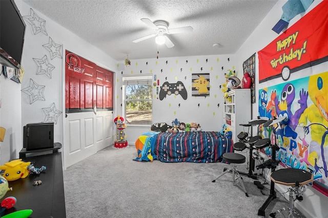 recreation room featuring carpet flooring, ceiling fan, and a textured ceiling