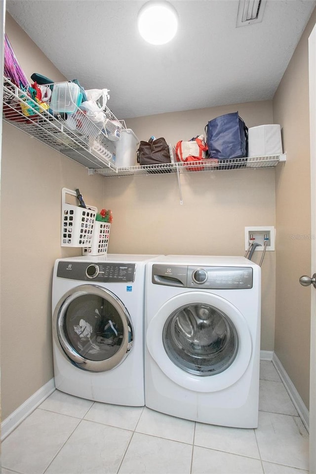 clothes washing area with light tile patterned floors and washer and dryer