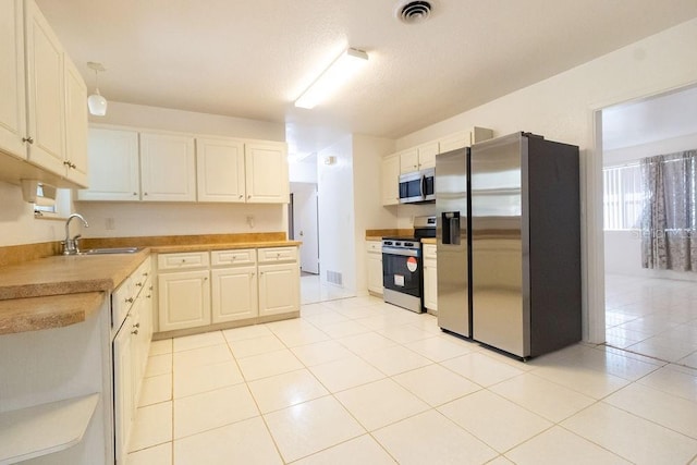 1068 N St, Daytona Beach, FL 32114 - kitchen with stainless steel appliances, a sink, light countertops, and light tile patterned flooring