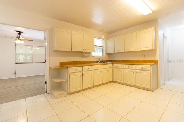 kitchen with light tile patterned floors, a textured ceiling, ceiling fan, and sink