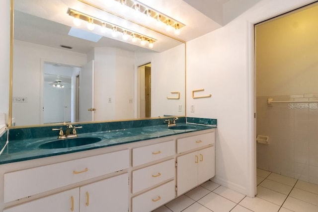 bathroom with vanity, a skylight, tile patterned floors, and ceiling fan