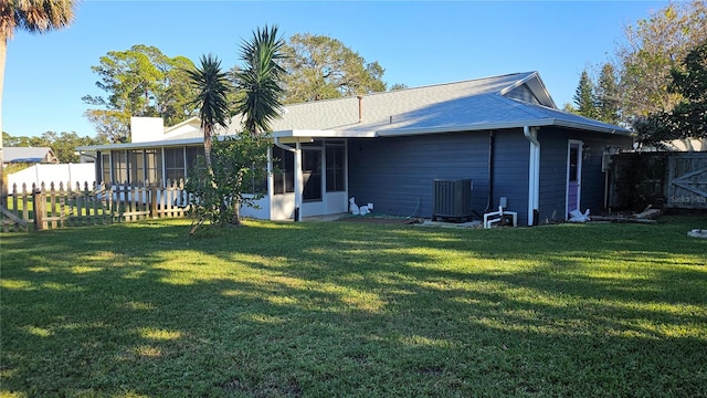 rear view of property featuring a lawn, a sunroom, and central AC unit