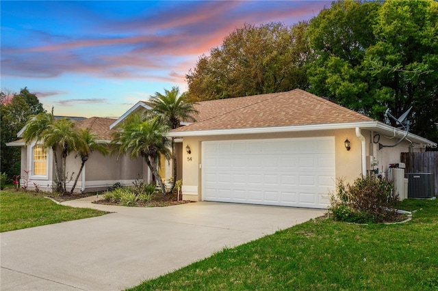 single story home featuring a lawn, central AC unit, and a garage