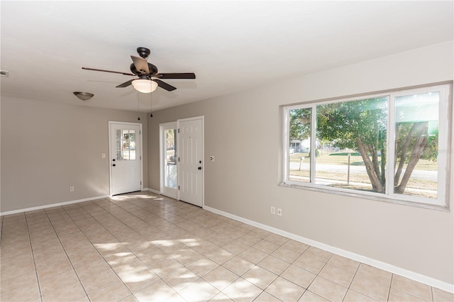 tiled empty room featuring plenty of natural light and ceiling fan