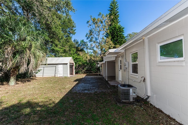 view of yard with a garage, an outdoor structure, and central air condition unit