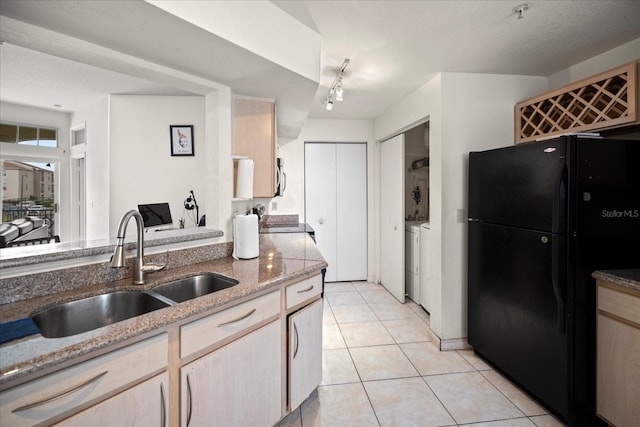 kitchen featuring light stone countertops, light brown cabinetry, sink, black appliances, and light tile patterned flooring