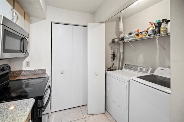 laundry area with washing machine and dryer and light tile patterned floors