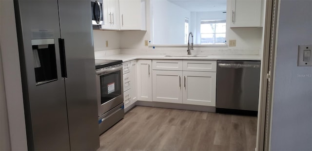 kitchen with white cabinets, appliances with stainless steel finishes, light wood-type flooring, and sink