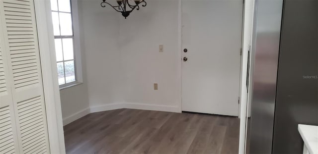 unfurnished dining area with dark hardwood / wood-style flooring and an inviting chandelier