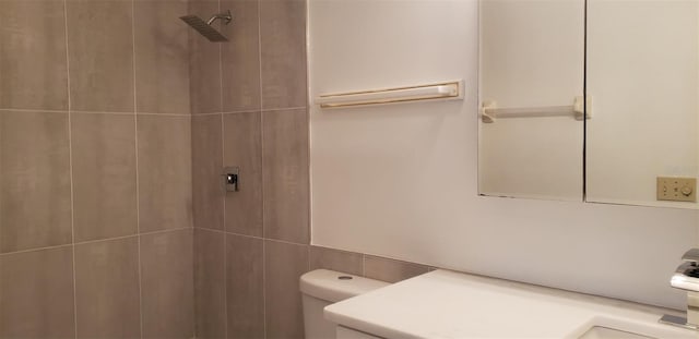 bathroom with vanity, toilet, and a tile shower