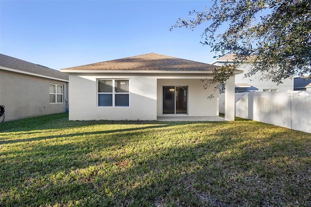 rear view of house with a lawn and a patio