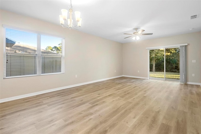 spare room featuring ceiling fan with notable chandelier, plenty of natural light, and light hardwood / wood-style floors