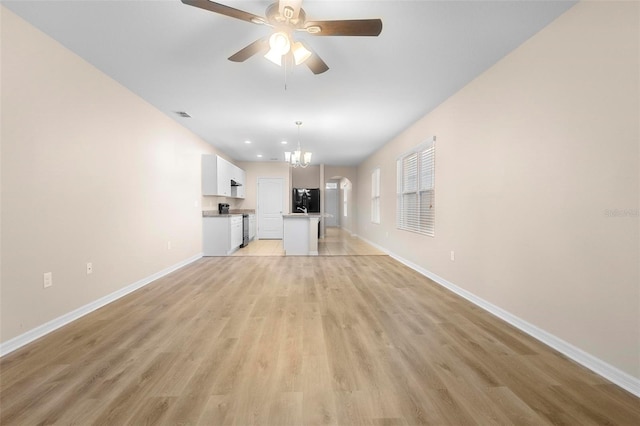 unfurnished living room featuring ceiling fan with notable chandelier and light wood-type flooring