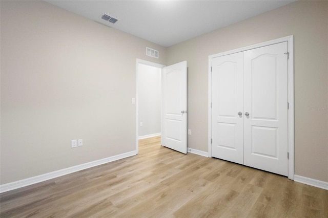 unfurnished bedroom with light hardwood / wood-style flooring and a closet