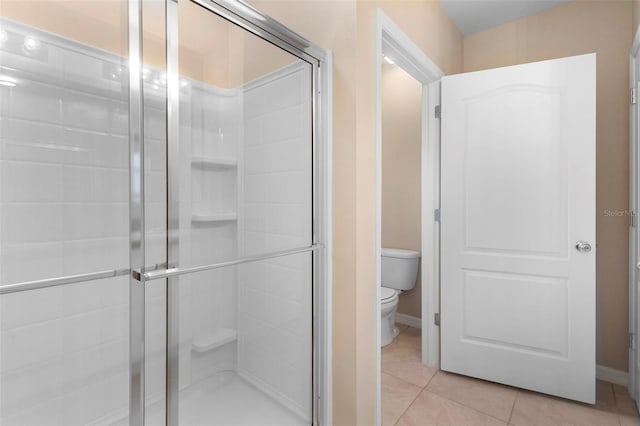 bathroom with walk in shower, toilet, and tile patterned flooring