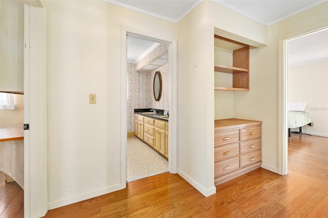 hallway with crown molding, sink, and light hardwood / wood-style flooring