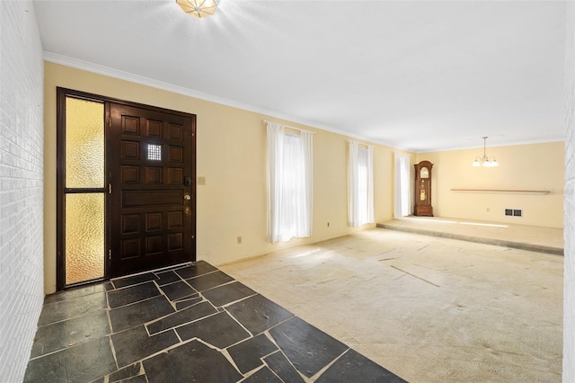 foyer entrance featuring dark colored carpet, a chandelier, and crown molding