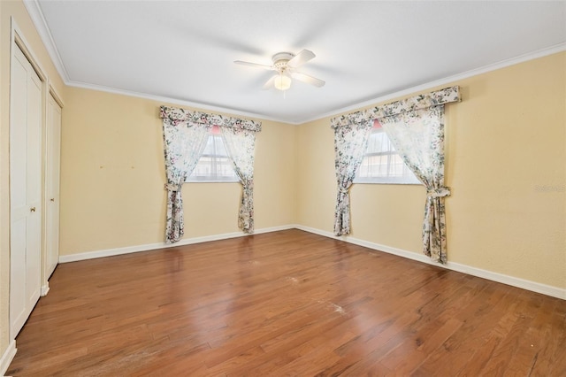 unfurnished bedroom with crown molding, a closet, wood-type flooring, and multiple windows