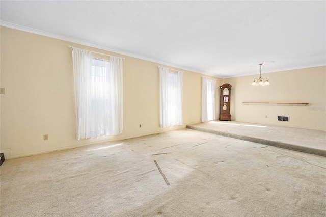 unfurnished living room with light colored carpet, ornamental molding, and a notable chandelier