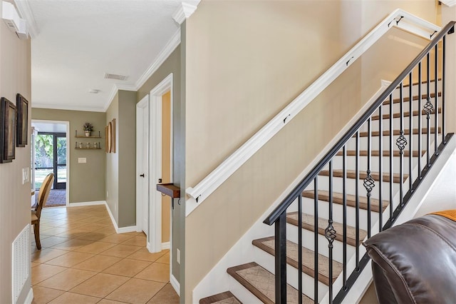 stairway with tile patterned floors and crown molding