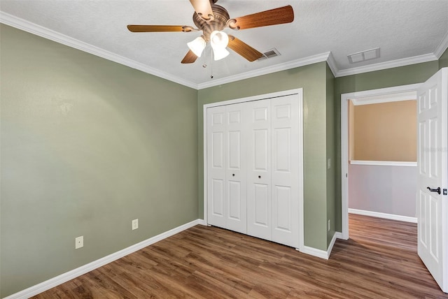 unfurnished bedroom with a closet, ceiling fan, hardwood / wood-style floors, and crown molding