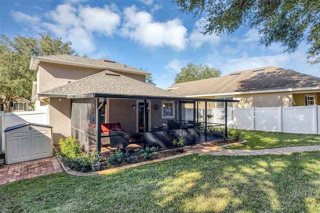 back of property featuring a sunroom, a storage unit, and a lawn