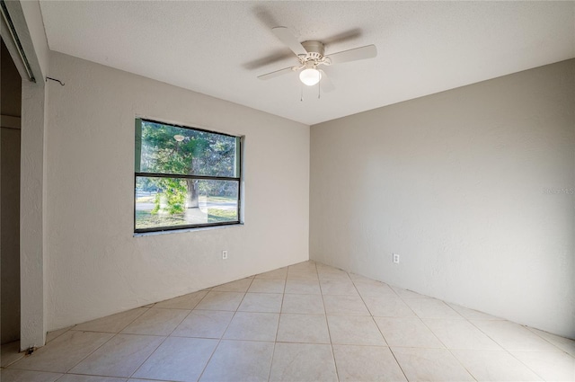 tiled empty room with ceiling fan and a textured ceiling