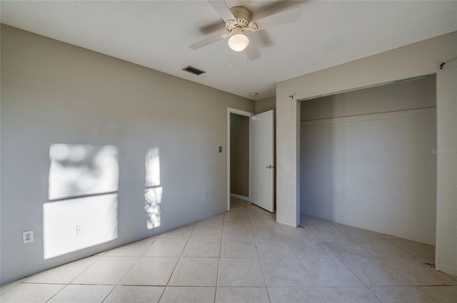 unfurnished bedroom featuring ceiling fan, light tile patterned floors, and a closet