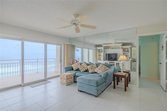 living room featuring ceiling fan, a water view, and a textured ceiling