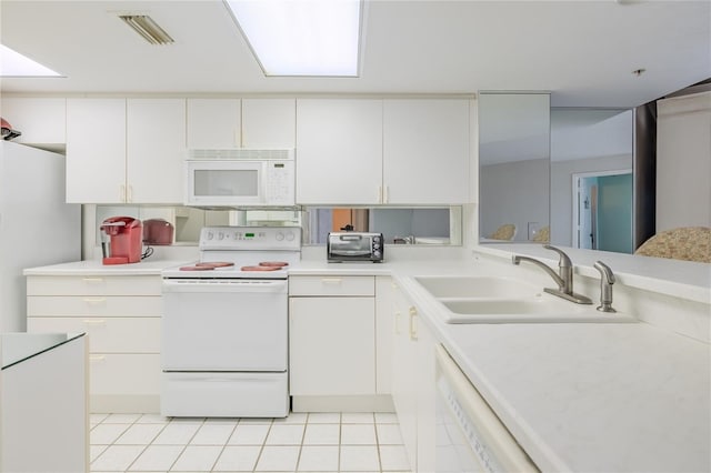 kitchen with kitchen peninsula, white appliances, sink, light tile patterned floors, and white cabinets