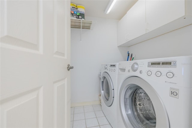 laundry area featuring washer and dryer, cabinets, and light tile patterned floors