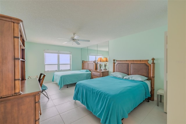 bedroom with ceiling fan, light tile patterned flooring, and a textured ceiling