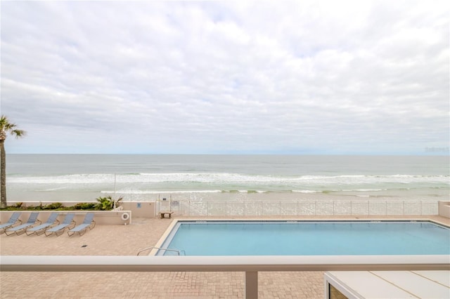 view of swimming pool featuring a water view and a view of the beach