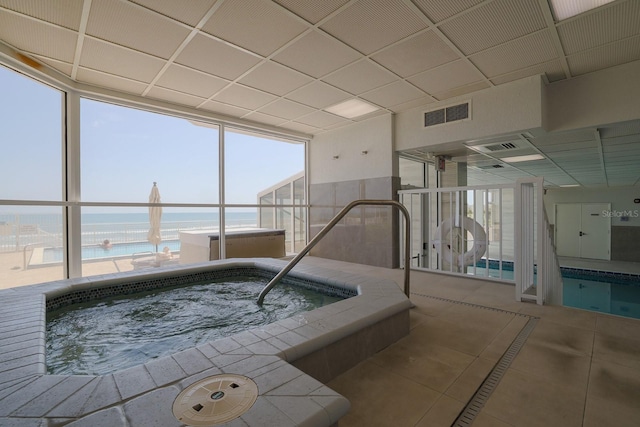 view of pool featuring a water view and an indoor hot tub