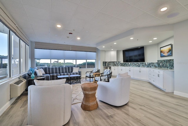 living room with light wood-type flooring and an AC wall unit