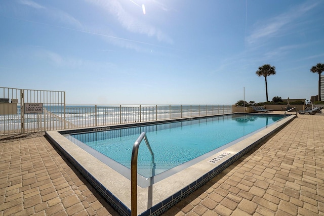 view of pool with a patio and a water view