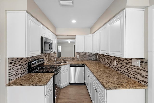 kitchen with white cabinetry, stainless steel appliances, and light hardwood / wood-style flooring